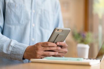 Close up hand of technology in use .  Man working in home office hand smart phone. Concept of using technology in communication.