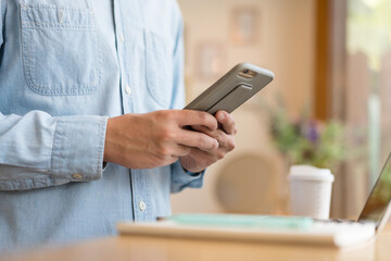 Close up hand of technology in use .  Man working in home office hand smart phone. Concept of using technology in communication.