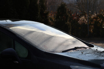 Słoneczny poranek topi lód na szybie samochodu. Wiosna. 