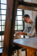 Young man working with clay on potter's wheel