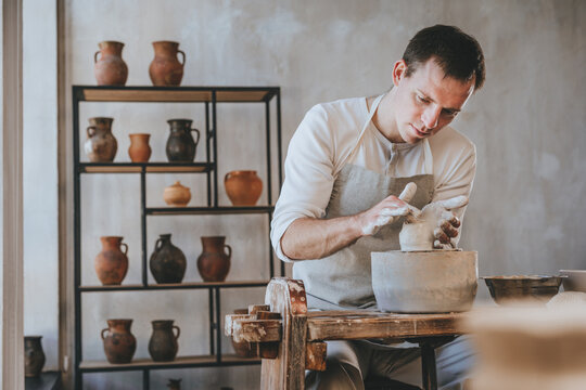 Young man working with clay on potter's wheel