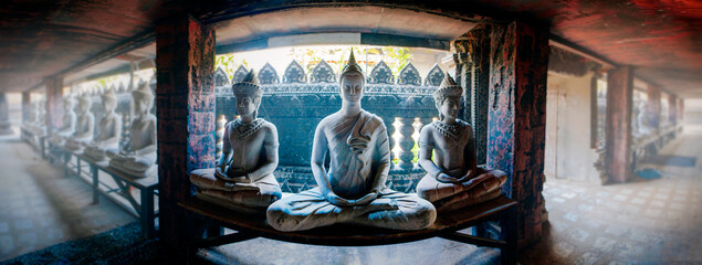 Buddha statues meditate in Wat Sa Kamphaeng Yai, Sisaket, Thailand. Wide-angle photo with the atmosphere of concentration.