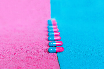pink and blue pills in line on pink and blue background. Pregnancy conception. Girl or boy