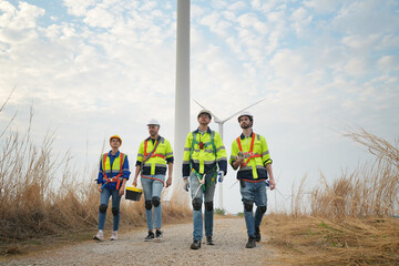 Wide perspective of wind turbine engineers walking with coworker in wind farms