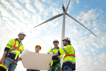 Wide perspective of wind turbine engineers walking with coworker in wind farms