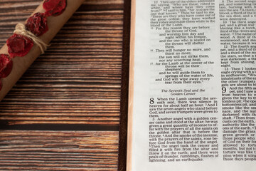 Revelation 8, open holy bible book on wooden table and old paper scroll with seven seals. Christian...