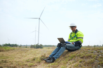 Wide perspective of wind turbine engineers walking with coworker in wind farms