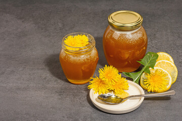 Dandelion jam or honey in the glass jar with fresh dandelion flowers. Trendy hard light, dark shadow