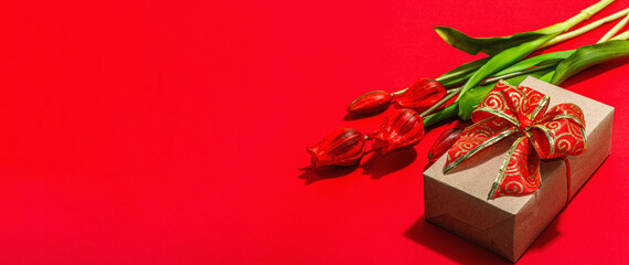 Valentine Day gift concept. Romantic red background with bright tulips bouquet, wrapped surprise box