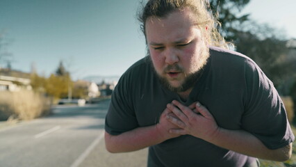 Person suffering from physical pain outdoors. Man unable to breath with hands on chest gasping for air having heart palpitations