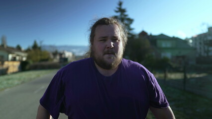 Fototapeta premium One angry overweight man walking outside. An upset young pensive person walks in street with dramatic expression. Regret emotion concept. Tracking shot