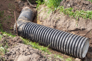 in the summer, a thick black water pipe lies in the ditch