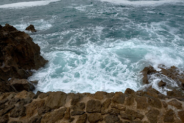 Fototapeta na wymiar Waves breaking on the shore on a pebble road