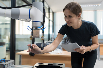 Female engineer training or maintenance AI robot in the manufacturing automation and robotics laboratory room