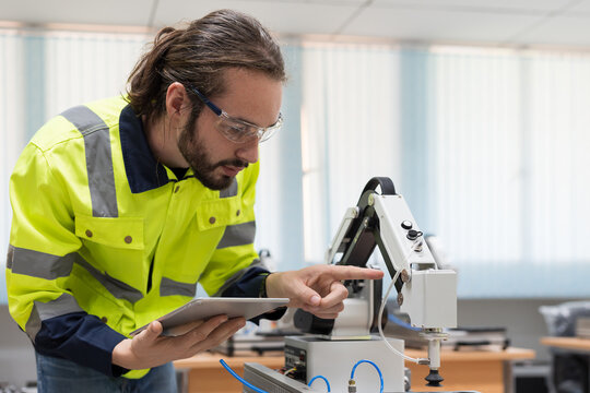Male engineer training or maintenance AI robot in the manufacturing automation and robotics laboratory room