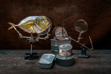 Still life with moonfish, canned food and a magnifying glass.