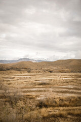 Snow capped mountains in western colorado behind dry brown rolling desert hills