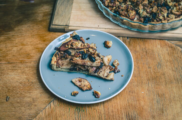 A piece of sweet cake with nuts, apples on a blue plate