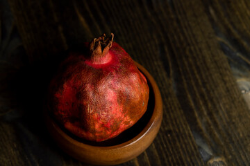 A small ripe red pomegranate is lying on the table