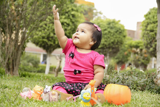 NI&Ntilde;A CON VESTIDO ROSA EN UN PARQUE JUGANDO Y SONRIENDO,TOMADA DE LA MANO DE SU MADRE, CONCEPTO DIA DEL NI&Ntilde;O Y CRECIMINETO Y DESARROLLO INFANTIL