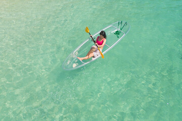 Aerial top view of Asian woman, a tourist, paddling a boat, canoe, kayak or surfboard with clear...