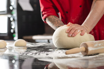 Fototapeta na wymiar pizzaiolo prepares pizza in the kitchen, the chef prepares the dough