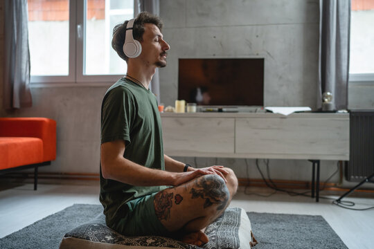 One Man Doing Guided Meditation Yoga Self Care Practice At Home