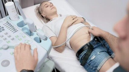 doctor does an ultrasound of the abdominal cavity of a young woman patient in a modern clinic