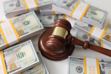 Wooden gavel and many us dollar bundles close up.