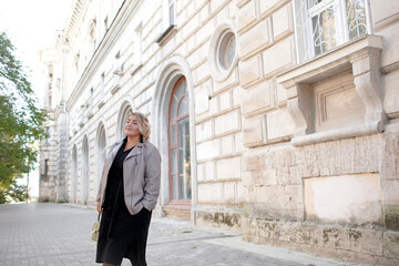 Beautiful woman plus size is walking around the city. The adult woman is wearing a black maxi stylish dress. A woman of large size