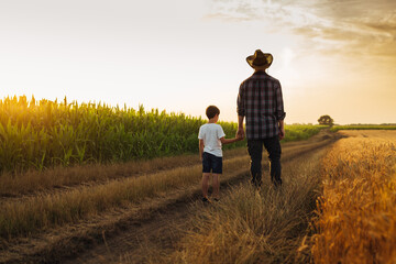 Father and son holding hands and walking on the country road