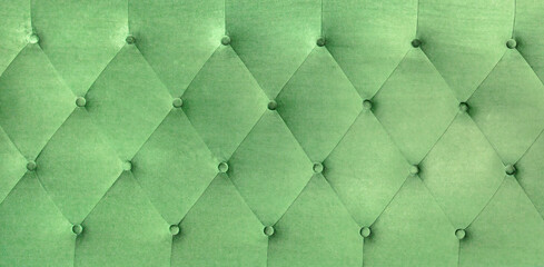 Background of green embossed fabric with buttons. Sofa upholstery