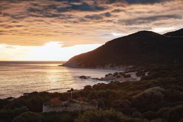 Fototapeta na wymiar Rocky Coast by the Sea. Sardinia, Italy. Nature Background. Cloudy Sunset Sky.