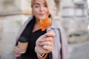 Beautiful woman plus size is walking around the city. The adult woman is wearing a black maxi stylish dress. A woman of large size holds the cup pf coffee