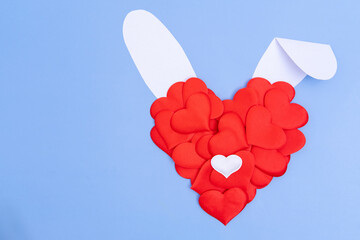 Creative greeting card. Imitation of the Easter bunny. A red heart and white paper ears on a blue...