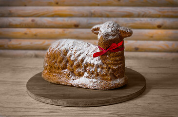 Lamb pastry with a red ribbon is a traditional food for Easter and Christmas. On a vintage brown wooden board in Rustic style.