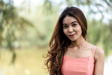 Naklejka premium Elegant pink dress with natural beauty featuring a smiling young woman leans on tree