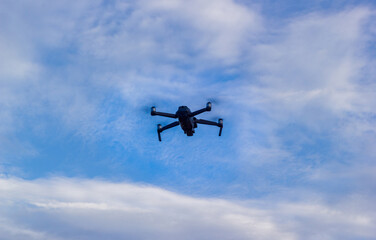 drone flies against the blue sky in the clouds