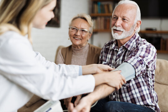 Female nurse checking blood pressure of a senior man during her home visit