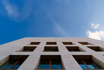 Abstract modern architecture. Low angle view of windows in facade against blue sky