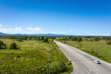 Asphalt highway through green tropical field. Aerial view