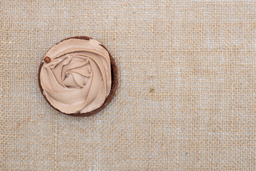 Fototapeta na wymiar Sweet chocolate tart with cocoa in the form of a rose on a natural cloth background