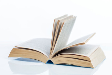 A thick open book lies on the table. Knowledge and education. Close-up. White background.