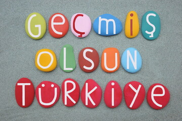 Gecims Olsun Turkiye, Get well soon Turkey, motivational slogan after the earthquake of February 2023 composed with multi colored stone letters over green sand