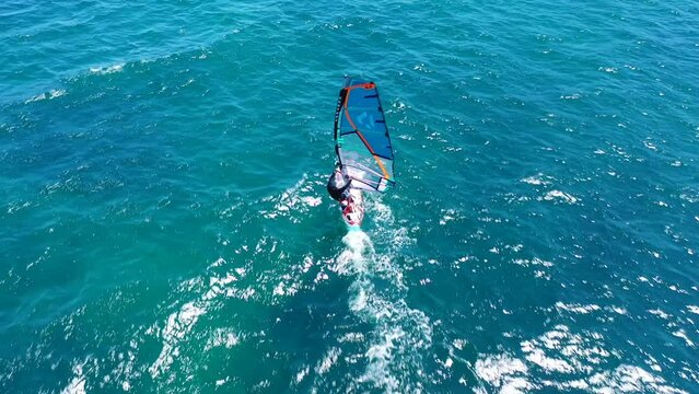 Aerial drone video of wind surfer cruising in high speed in tropical wavy deep blue ocean bay