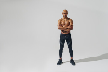 Attractive sporty man with muscled naked body on white studio background looking at camera