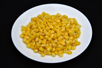 Fresh canned corn on a white plate. Corn salad. Yellow corn kernels.