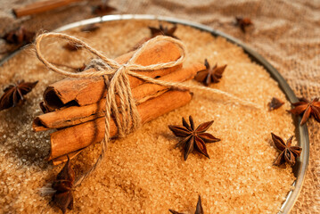 A bunch of cinnamon sticks, on cane sugar, with anise stars. Against the background of burlap.