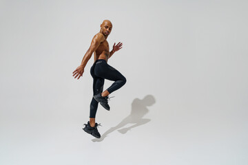 Fototapeta na wymiar Active sporty man with naked torso jumping on white studio background. Sport and healthy lifestyle
