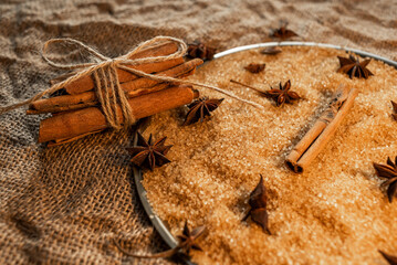 A bunch of cinnamon sticks, on cane sugar, with anise stars. Against the background of burlap.